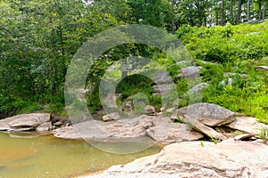 A majestic shot of the silky brown waters of the Chattahoochee river with lush green trees and rocks along the banks of the river