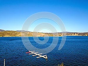 A majestic shot of the still deep blue lake waters, gorgeous mountain ranges and blue sky at Castaic Lake