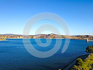 A majestic shot of the still deep blue lake waters, gorgeous mountain ranges and blue sky at Castaic Lake