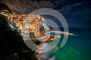 Majestic shot of the turquoise ocean and the lighted coastline of colorful buildings at nighttime