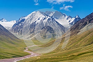 Majestic snow capped mountain peak with green alpine meadows