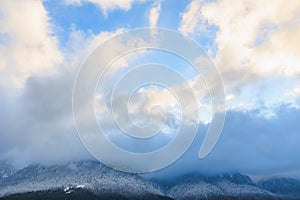 Majestic snow-capped mountains under clear blue sky with clouds