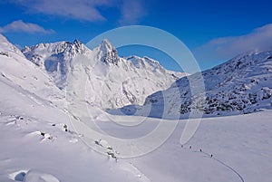 Majestic snow capped Rocky Mountains surround a group of tourists ski touring.