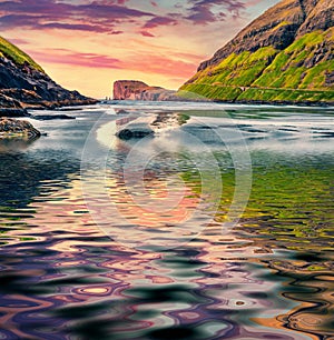 Majestic summer sunrise on Tjornuvik beach, Faroe Islands with Eidiskollur cliffs reflected in the calm waters of Atlantic ocean.