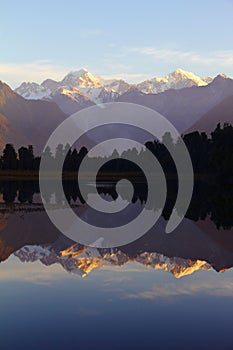 Majestic sunset at Lake Matheson with a reflection of Mount Cook and Mount Tasman in New Zealand.