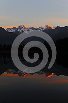 Majestic sunset at Lake Matheson with a reflection of Mount Cook and Mount Tasman, New Zealand.