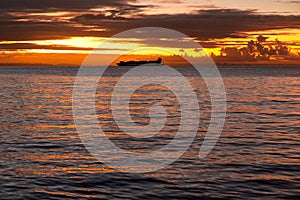Majestic sunset over a tranquil ocean with a ship in the dstance