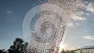 Majestic video animation of cropped water shower rain flow from sprinkler, air sprayer, pulverizer against trees and sky