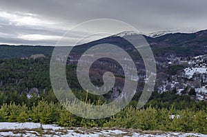 Majestic view of cloudy sky, winter mountain, snowy glade, residential district, conifer and deciduous forest from Plana mountain