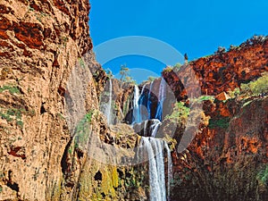 Majestic Waterfall Cascading Down Rocky Cliffs Under a Blue Sky