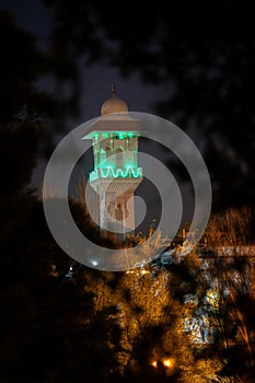 A majestic white mosque with a illumined ted tower after Ramadam.