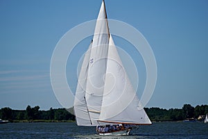 Majestic white sailboat on blue water under a bright blue sky