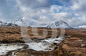 Majestic Winter landscape image of River Etive in foreground with iconic snowcapped Stob Dearg Buachaille Etive Mor mountain in photo