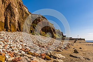 Major rockfalls from the white, red and orange stratified cliffs towards the sea wall at Old Hunstanton, Norfolk, UK