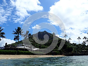 Makalei Beach with waves lapping, napakaa, lava rock wall and Coconut trees along the shore