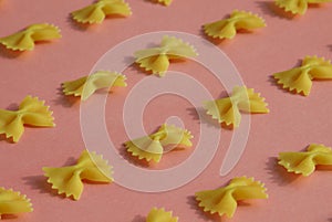 Makaroni or pasta bow shape in row on pink background