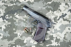 Makarov pistol with cartridges on the background of military camouflage pixel.