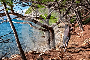 Makarska - Hiker woman on idyllic hiking trail in coniferous forest along tropical stone beach in summer