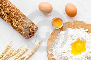 Make bread concept. Bread near wheat ears, flour and eggs on white background top view