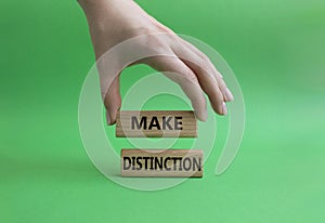 Make distinction symbol. Concept words make distinction on wooden blocks. Beautiful green background. Businessman hand. Business photo