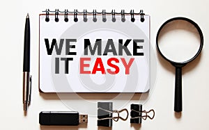 We make it easy text in the notebook on a wooden table. Top view - business concept