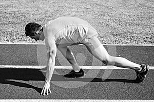 Make effort for victory. Man athlete runner stand low start position stadium path. Runner ready to go. Adult runner