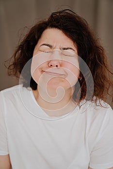 make faces. brunette woman with curly hair in a white T-shirt.