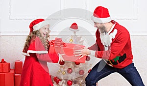 Make it fun. Kid cute girl play with father near christmas tree. Playful daughter and dad celebrate christmas. Winter