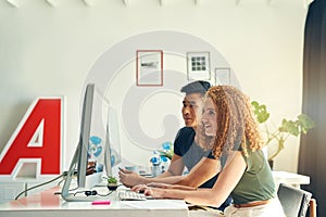 They make a great team. two young creative businesspeople working on a computer in their office.