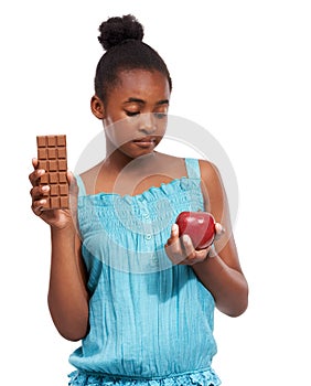 Make the healthy choice. a young african american girl trying to decide between eating an apple or an a piece of