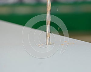 Make a hole with a drill in a wooden board using an electric drill.