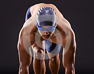 Make the laps count. Studio shot of a handsome swimmer ready to dive off the starting block.