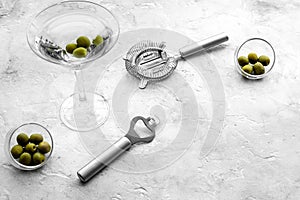 Make martini cocktails. Glass with beverage, olives and utensils on grey stone background top view copyspace