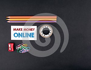 Make money online. Top view of a black ofice desk. Colored pencils, business card and adhesive tape