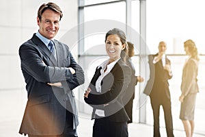 They make a perfect pair. Cropped portrait of two businesspeople standing a lobby with their colleagues in the