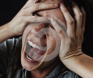 Make it stop. A young woman screaming uncontrollably while isolated on a black background.