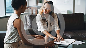 They make such a great team. two businesspeople having a discussion while sitting on a couch in a modern office.