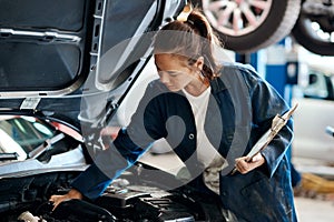 Make sure your car is up-to-date with its maintenance. a female mechanic working on a car in an auto repair shop.