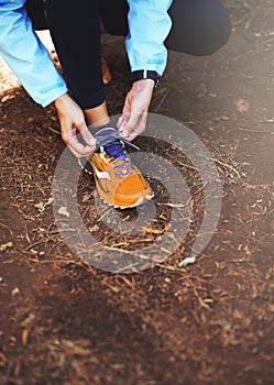 Make sure your shoes are snug. a woman tying up her running shoes before a trail run.