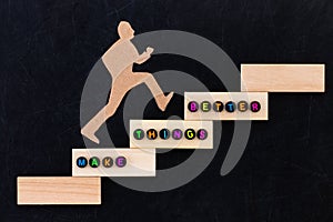 Make things better - Improvement Concept. paper man climbing the steps to success in a conceptual image over black background