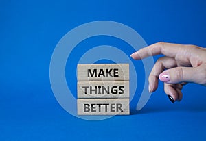 Make things better symbol. Concept word Make things better on wooden blocks. Businessman hand. Beautiful blue background. Business