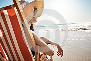 Make time for the things that make you happy. an attractive young woman relaxing on chair at the beach.
