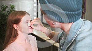 make-up artist applies powder on face of model