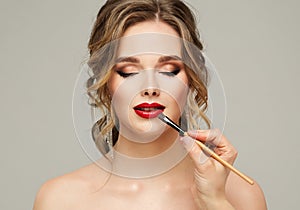 Make up Artist apply Red Lipstick. Beauty Woman Model put on Lip Gloss. Close up Portrait of Professional Makeup Master Hand with