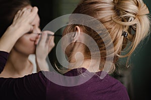 Make-up artist applying bright base color eyeshadow on model's eye