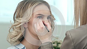 Make-up artist applying eye shadow makeup to model face