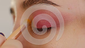 Make-up artist applying eye shadow makeup to model`s eye. Close up view. Smoky eyes. Left view. slow motion. makeup