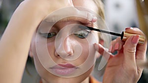 Make-up artist applying eyelash makeup to model`s eye. Mascara .Close up view