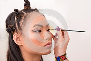 Make-up Artist Applying Eyeliner on Asian Young Woman`s Face with Make-up Brush, on White Background