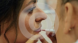 Make up artist applying lipstick. close-up of the lips of a young woman, professional makeup artist with a brush applies